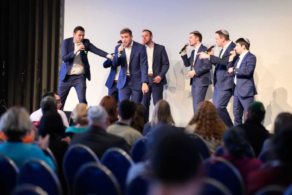 A cappella group performing on stage for a seated audience