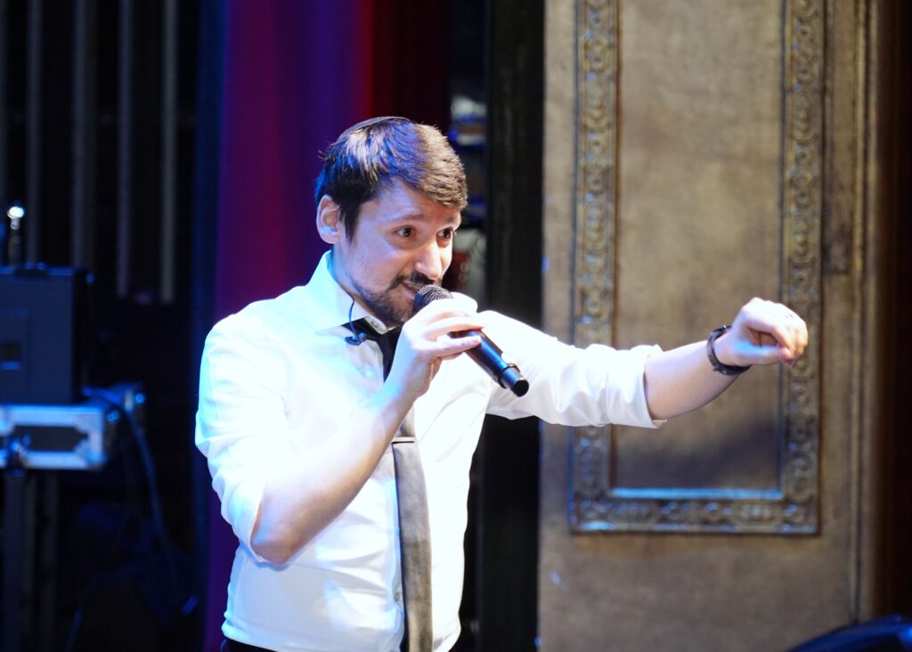 Cory Hecht singing into a microphone on stage